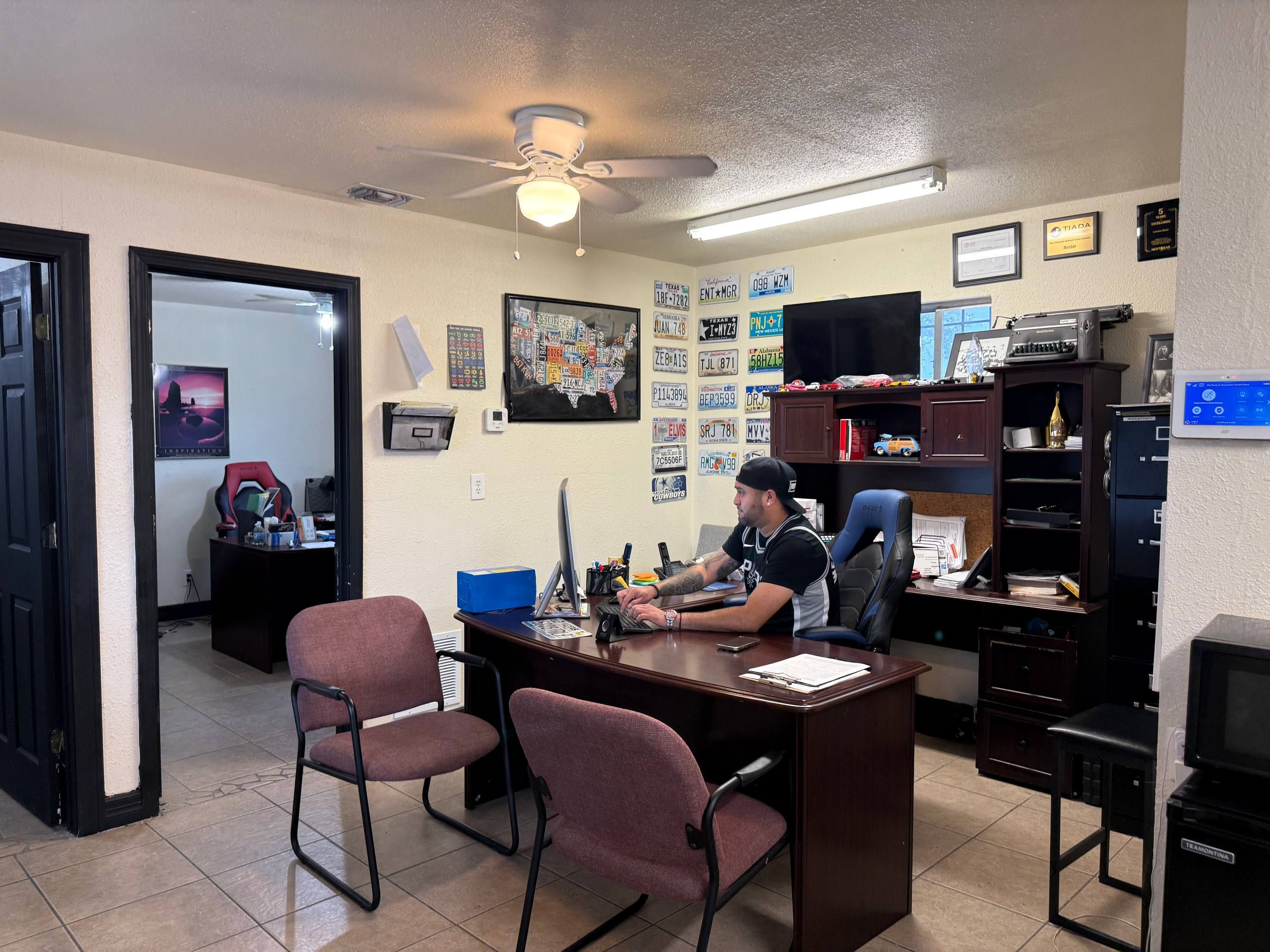 The Aleman Auto Sales office and its wall of Texas license plates.