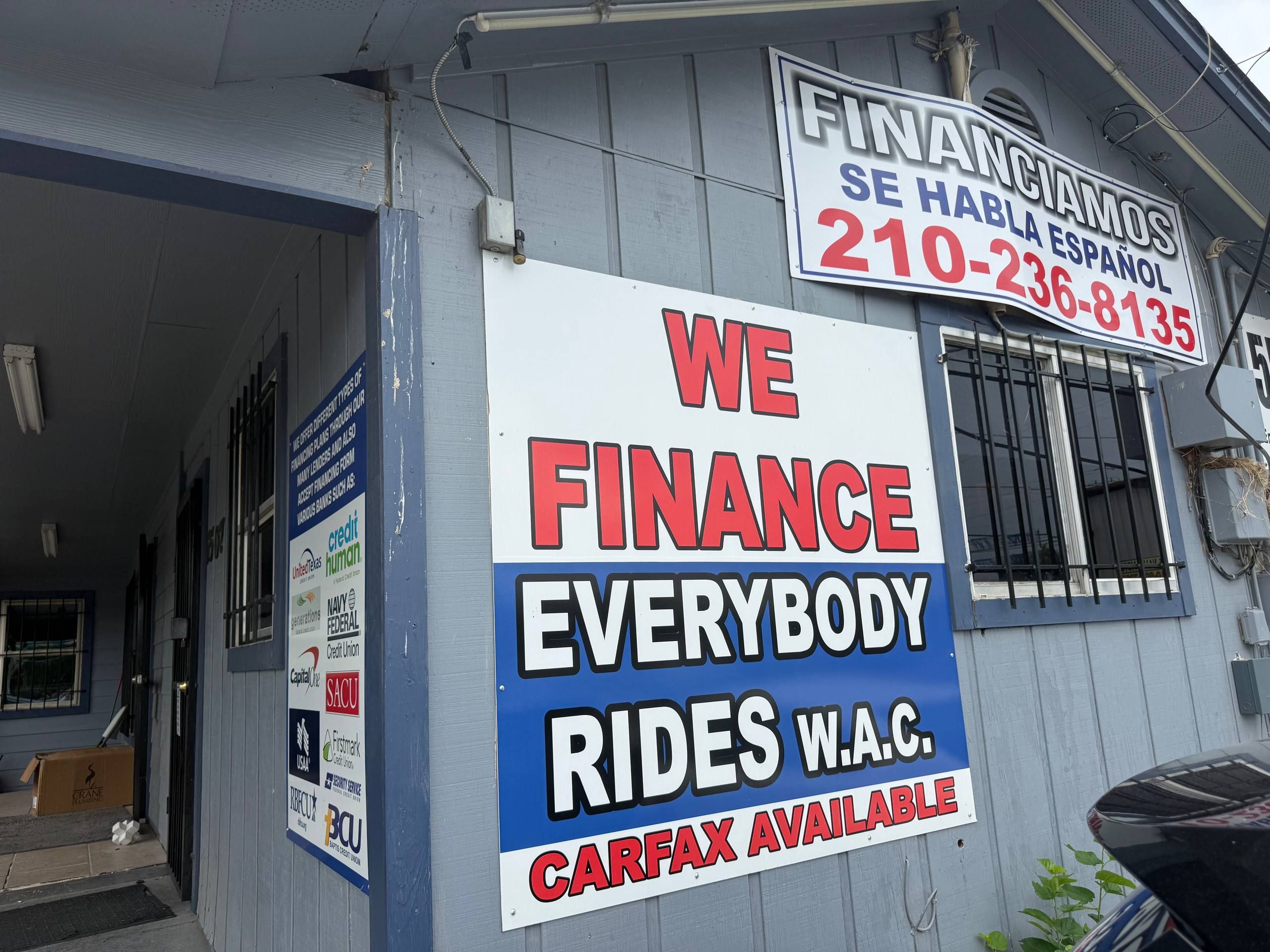The 'We Finance Everybody — Rides W.A.C.' wall at Aleman Auto Sales.